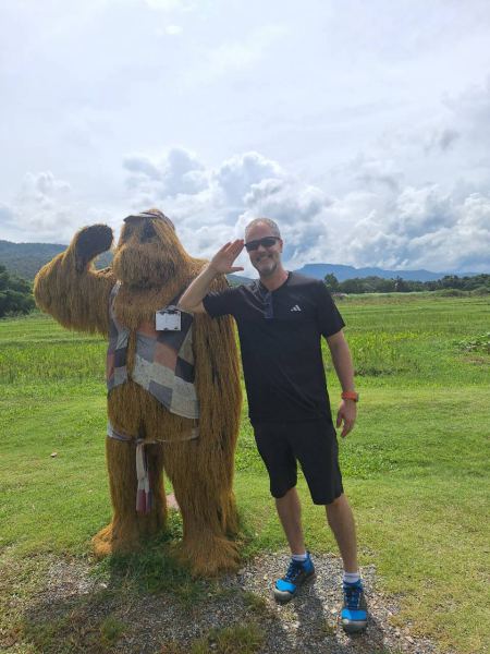 A guest saluting a giant straw sasquatch in the rice field - lifeonwheel.com