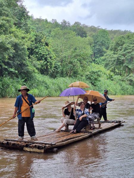 Sheltering under umbrellas on the bamboo raft - lifeonwheel.com