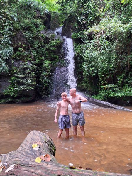 Father and son standing together beneath the falls - lifeonwheel.com
