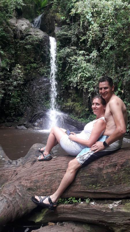A couple resting on a fallen log by the waterfall - lifeonwheel.com