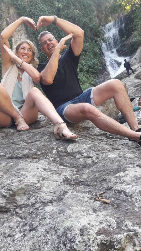 A couple making a heart sign by the falls - lifeonwheel.com